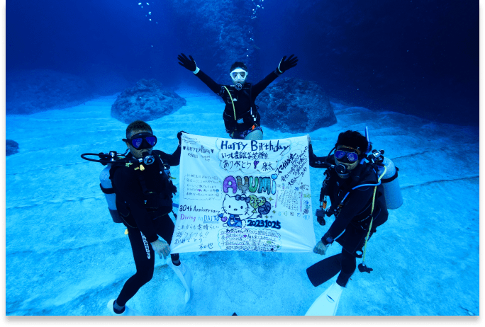 ３人のダイバーが水中で幕を広げている様子